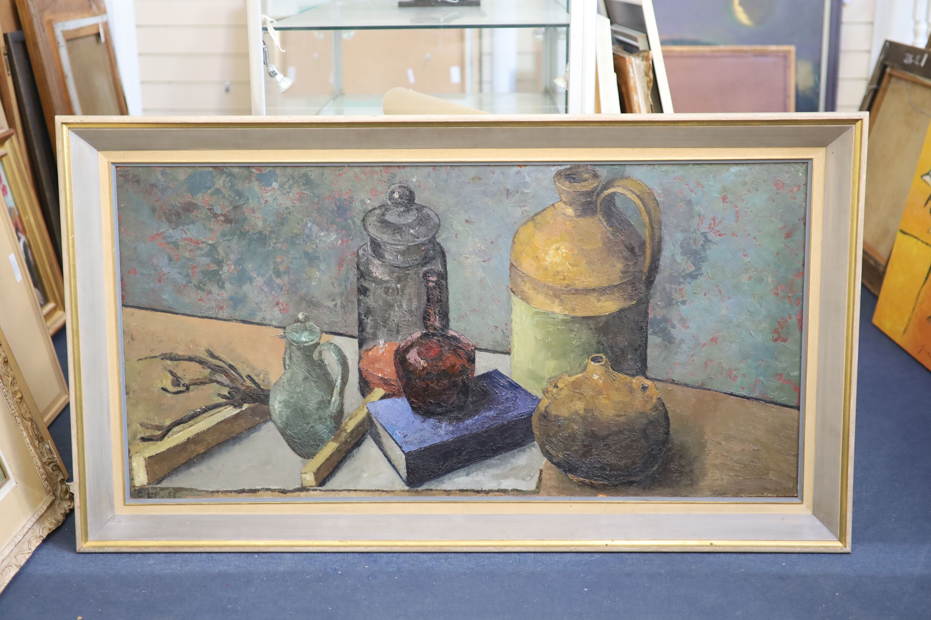 Clarisse Loxton-Peacock (1926-2004), Still life of bottles, a book and flagon on a table top, oil on board, 60 x 121cm